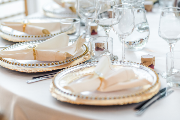 A close up of a wedding table set with glassware, plateware and white linens