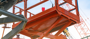 A close up of an orange boom lift at sunset