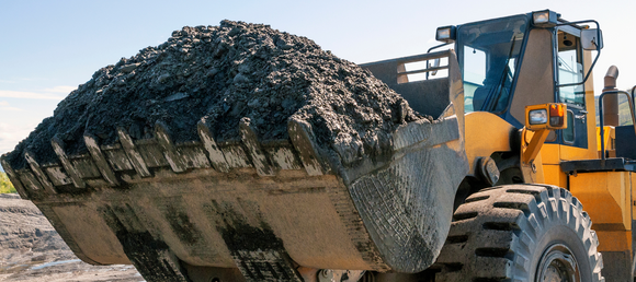 A large excavator carrying soil in it's bucket